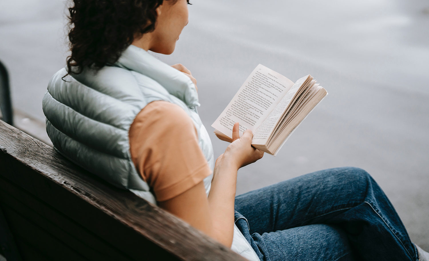 An introvert reads on a park bench