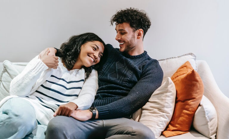 A couple cuddles and laughs together on the couch