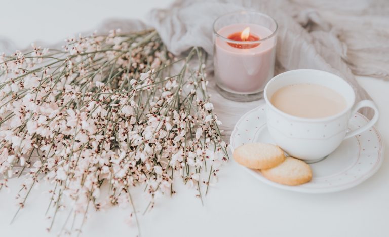 a candle, cookies, coffee, and flowers, representing an introvert's hygge all year round