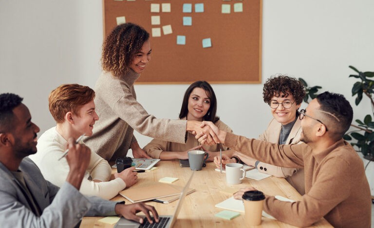 Two introvert employees shake hands at a work meeting
